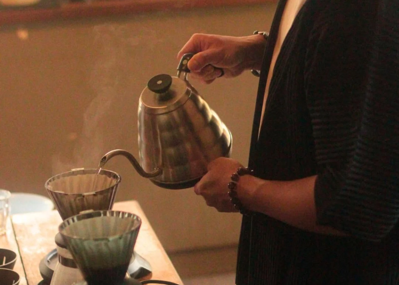 A barista pours water from a gooseneck kettle into a coffee dripper at Commune.